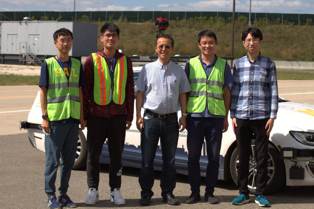Photograph of Henry Liu and the Michigan Traffic Lab team in front of their Level 4 autonomous vehicle. From left to right: Shengyin Shen, Xintao Yan, Dr. Henry Liu, Dr. Shuo Feng, and Haojie Zhu 