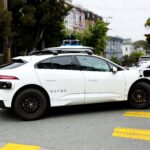 A Waymo robotaxi drives through an urban environment