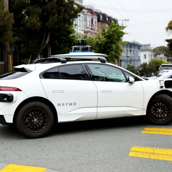 A Waymo robotaxi drives through an urban environment